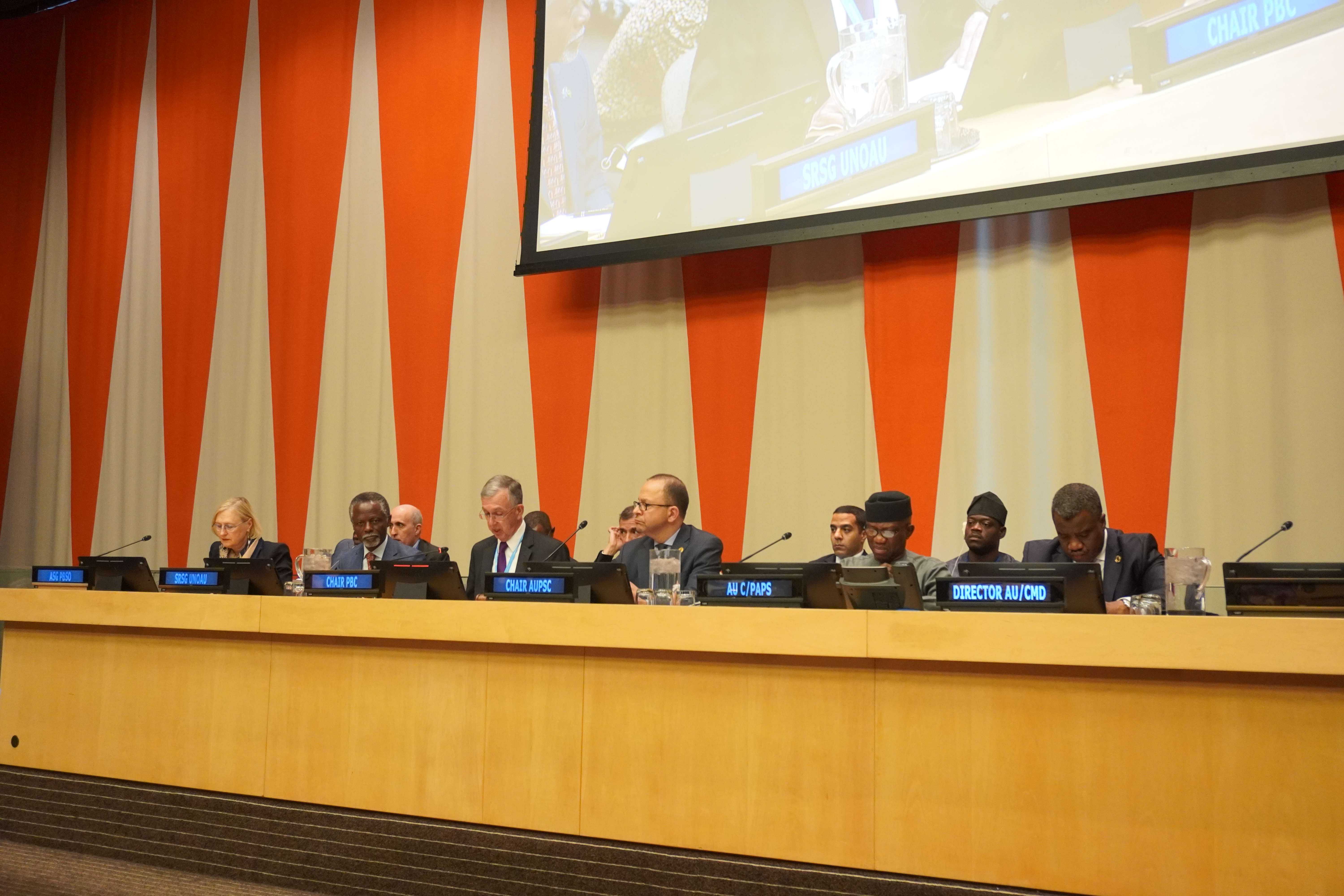 A group of people sitting at a podium

Description automatically generated