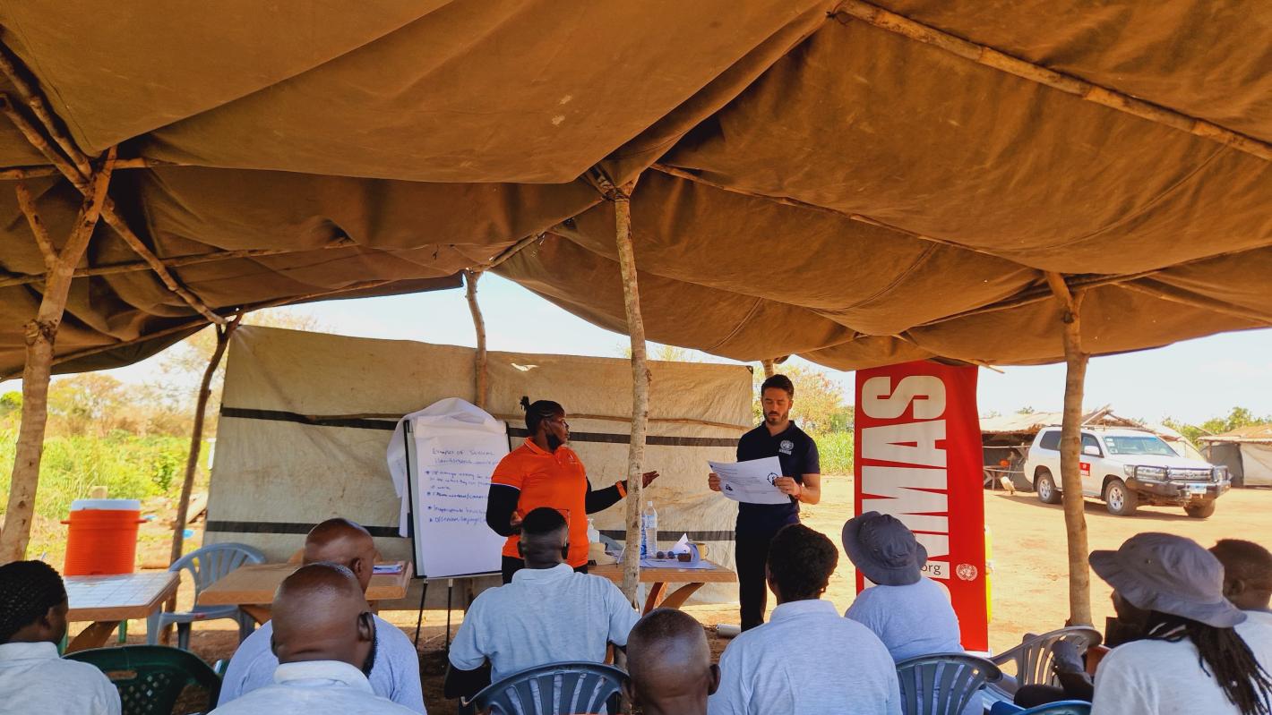 a man and a woman are standing in front of a couple of deminers sitting in chairs.