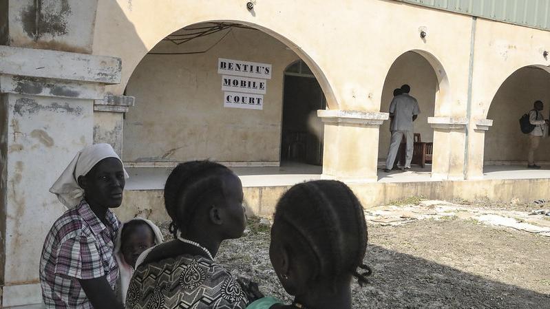 Mujeres sentadas en un banco frente al tribunal móvil de Bentiu.