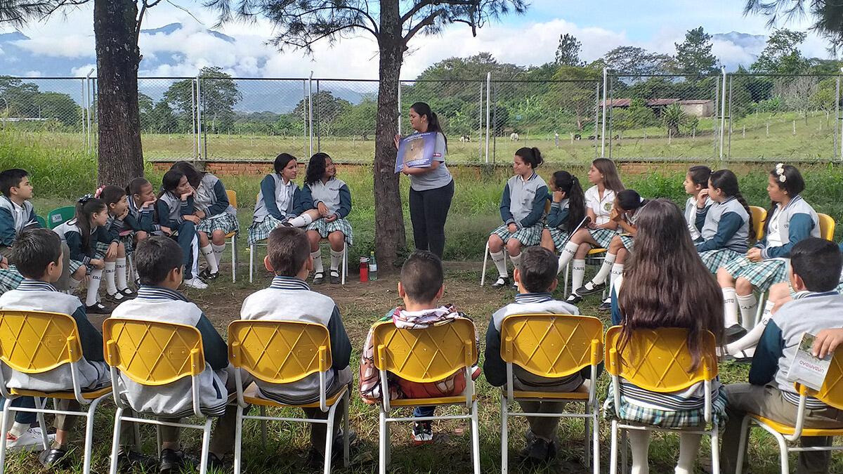 a woman is presenting a poster to a group of students sitting around