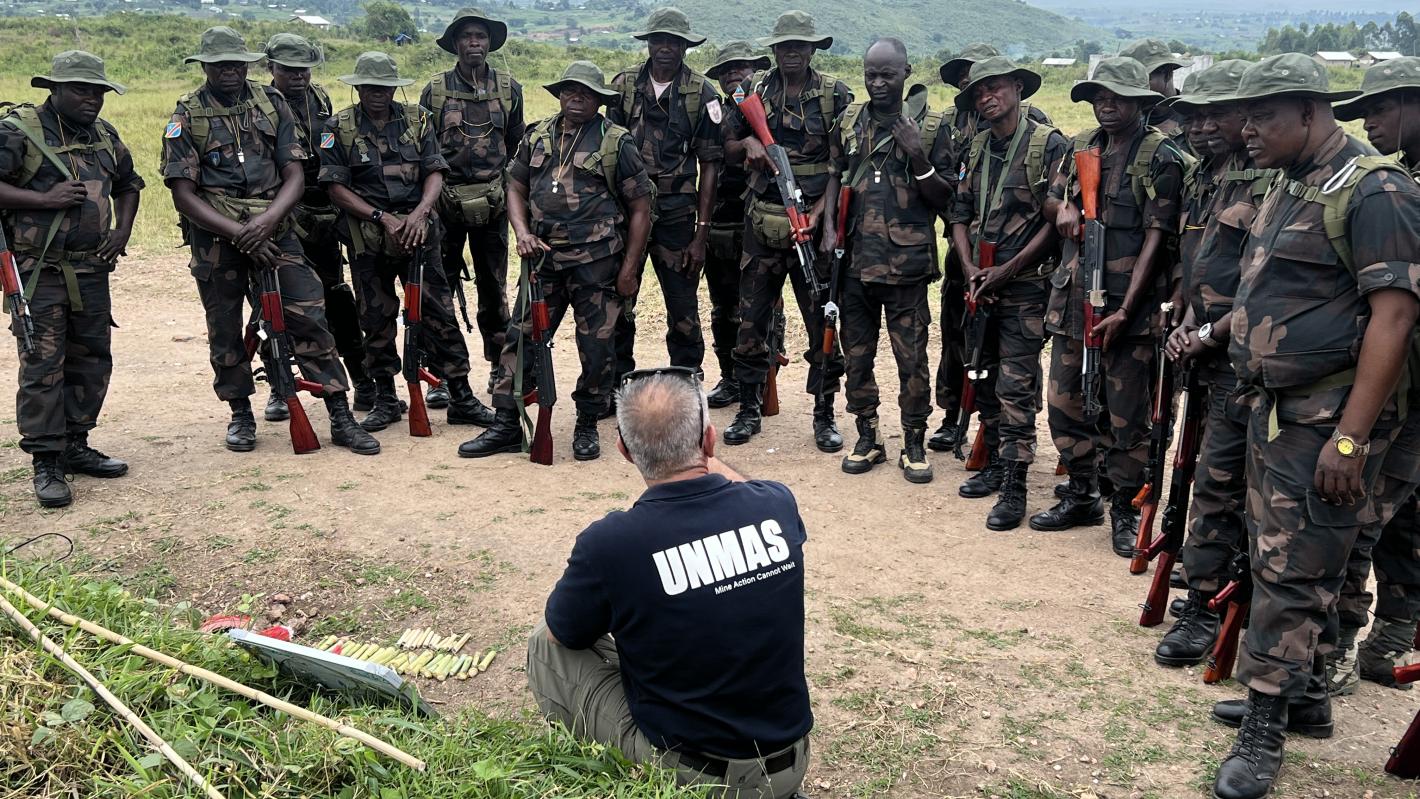 an unmas staff is showing something to a group of soldiers