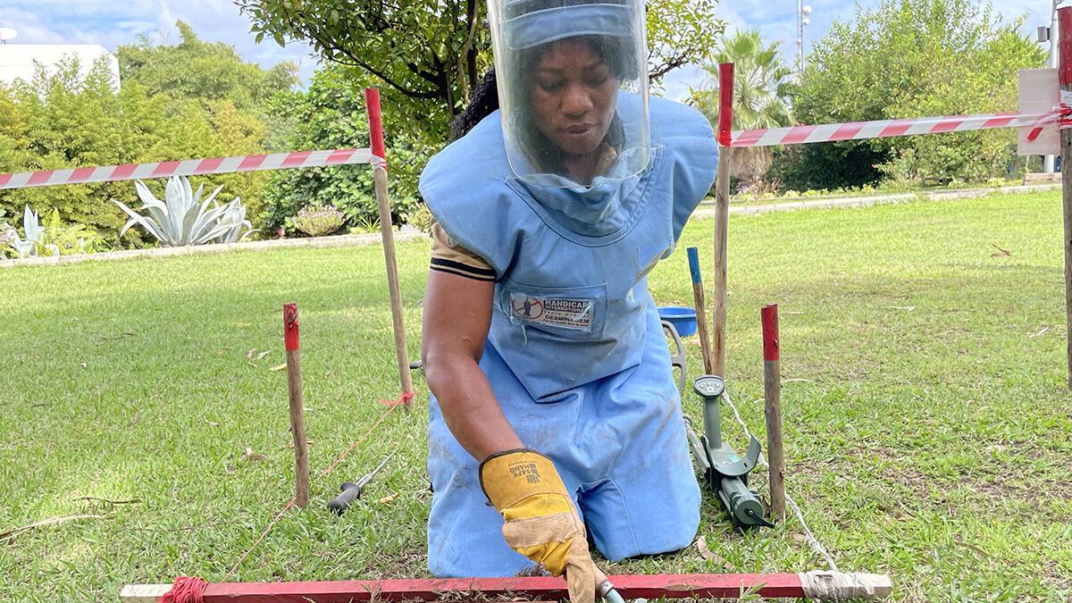 a female deminer is working in a field