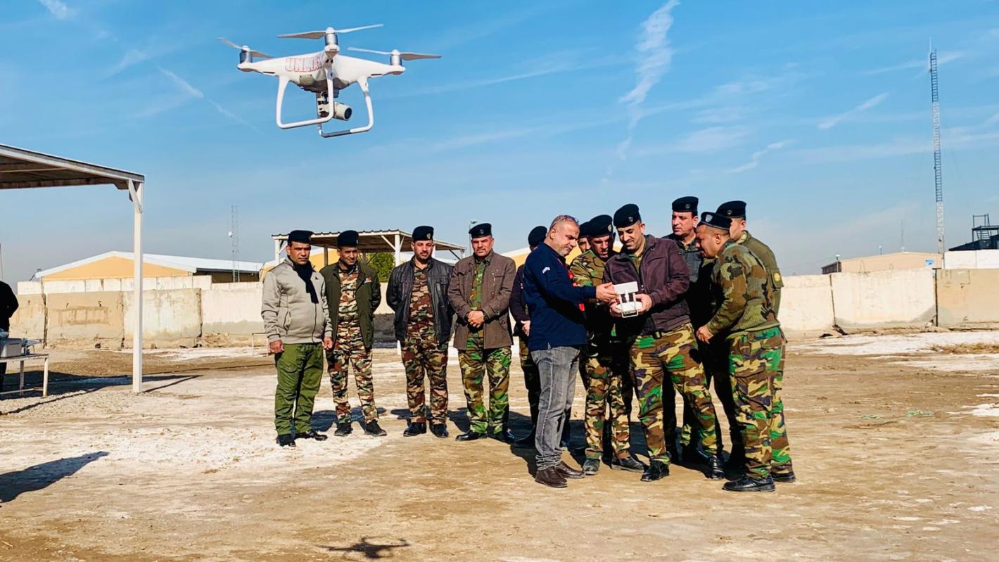 some men with uniforms are getting trained with a drone flying in front of them