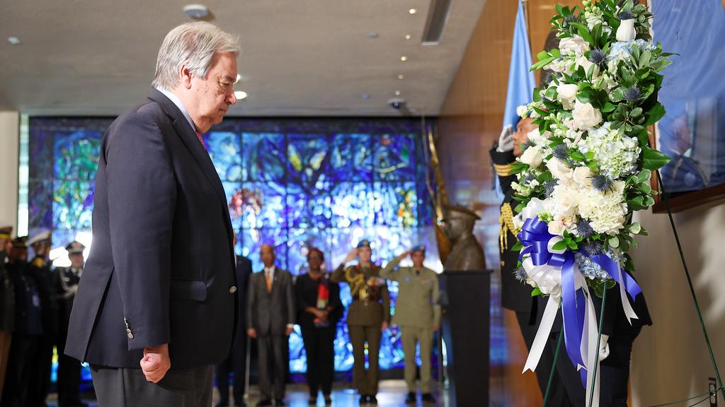 UN Secretary General stands soberly in front of a wreath