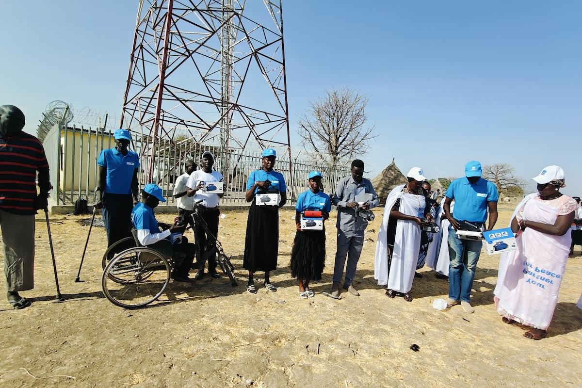 A new Radio Miraya transmitter was launched in Mayom during an event that also celebrated International Women's Day. Photos: Taban Geofrey Koma Alfred/UNMISS A group of people standing in front of a radio transmitting tower.