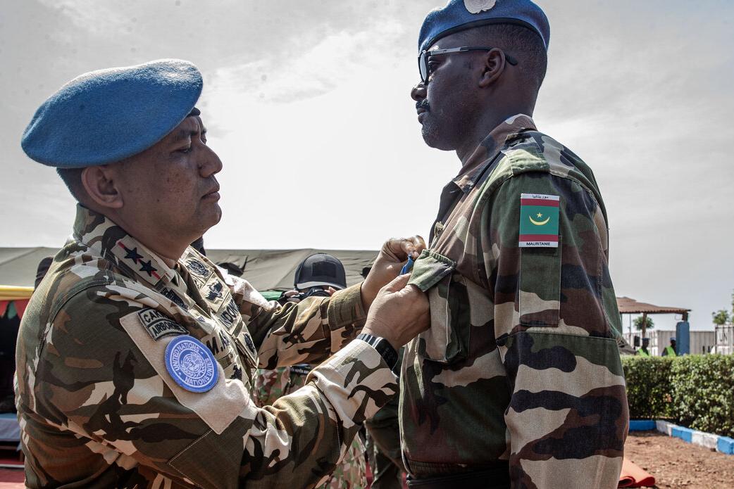 Un homme en uniforme militaire épingle une médaille sur un autre homme en uniforme militaire.