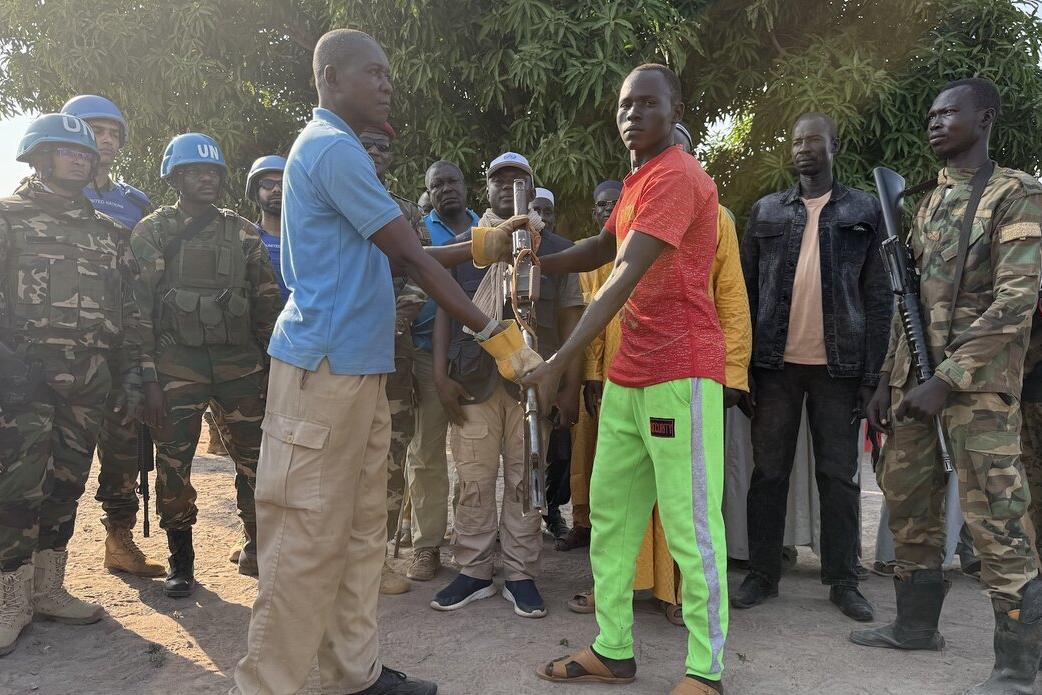 Deux hommes se serrent la main devant un groupe de soldats de la paix en uniforme militaire.
