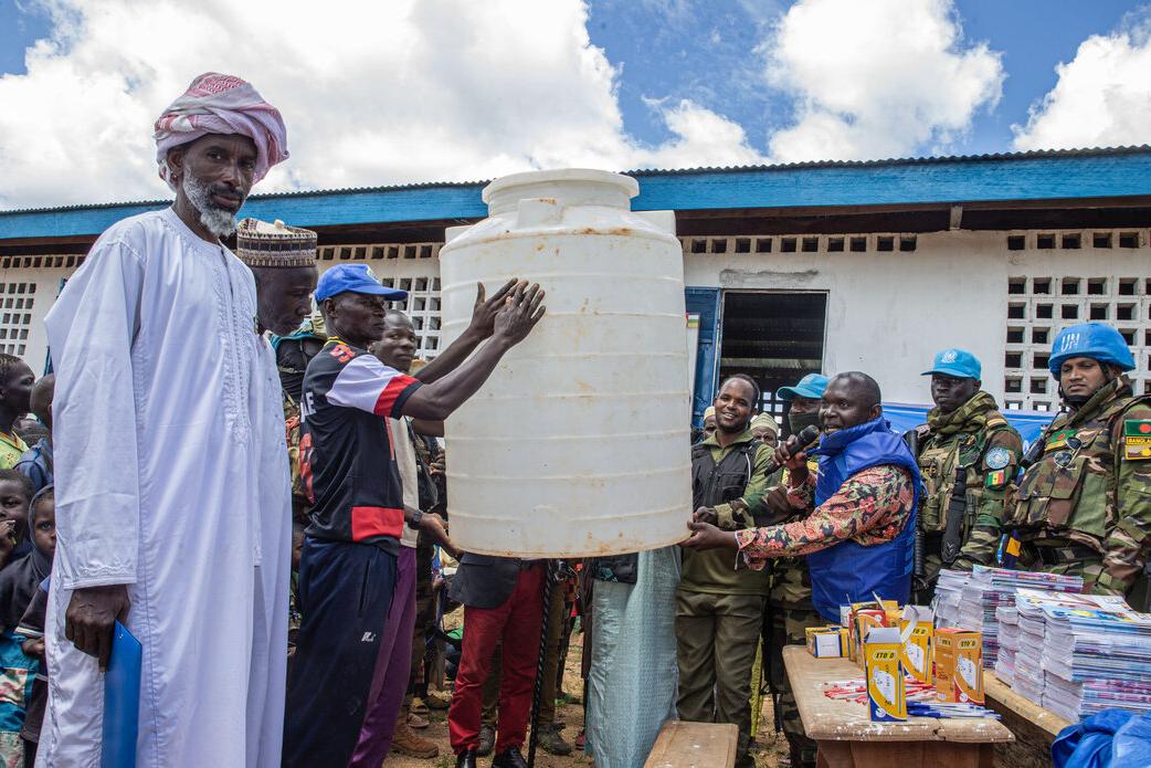 A group lifts equipment outdoors.