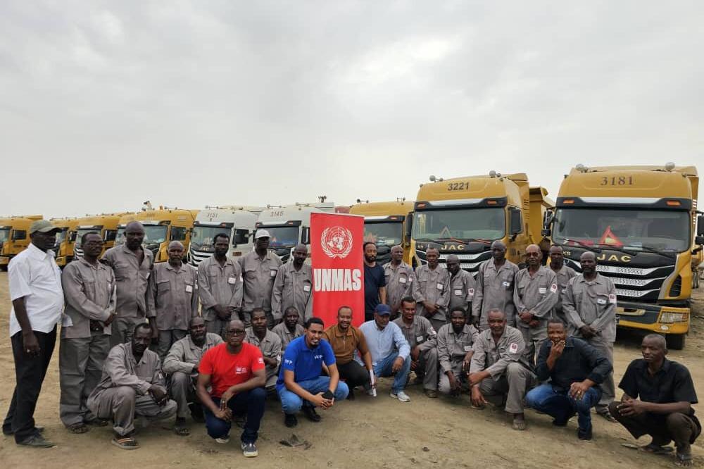 a group of men in front of several trucks