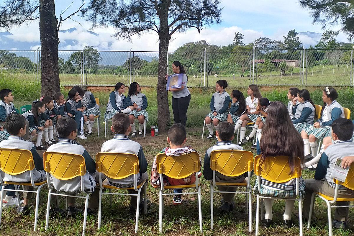 a woman is presenting a poster to a group of students sitting around