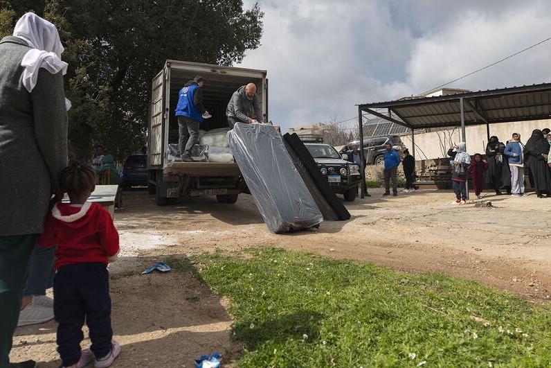 Des travailleurs de l'Organisation internationale pour les migrations (OIM) distribuent des matelas à une famille au Liban