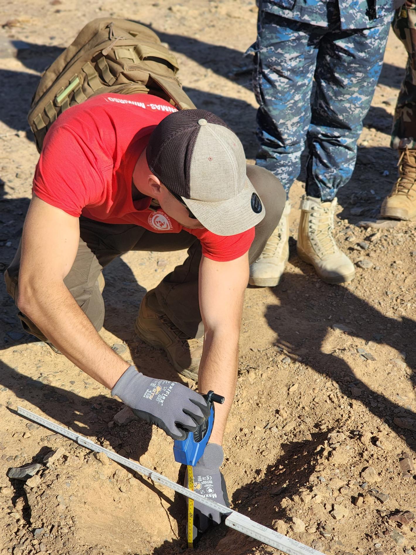 a man is measuring the with of a hole on the ground