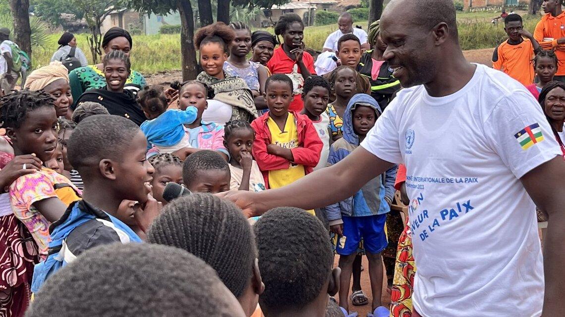 Un Casque bleu en civil tend un microphone à un jeune, au milieu d’un groupe de jeunes membres de la communauté.